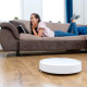 Robotic vacuum cleaner cleaning the room. Woman is lying on the bed. Smart home concept