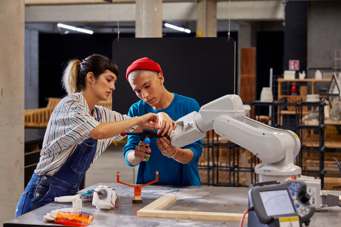 Male and female classmates working with robotic equipment at desk in university