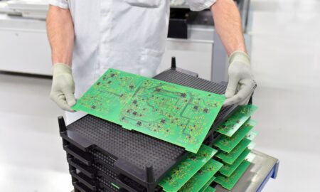 Arbeiter hält Platine mit Mikroelektronik in einer Fabrik Produktion von High Tech Bauteilen // Worker holding circuit board with microelectronics in a factory production of high tech components